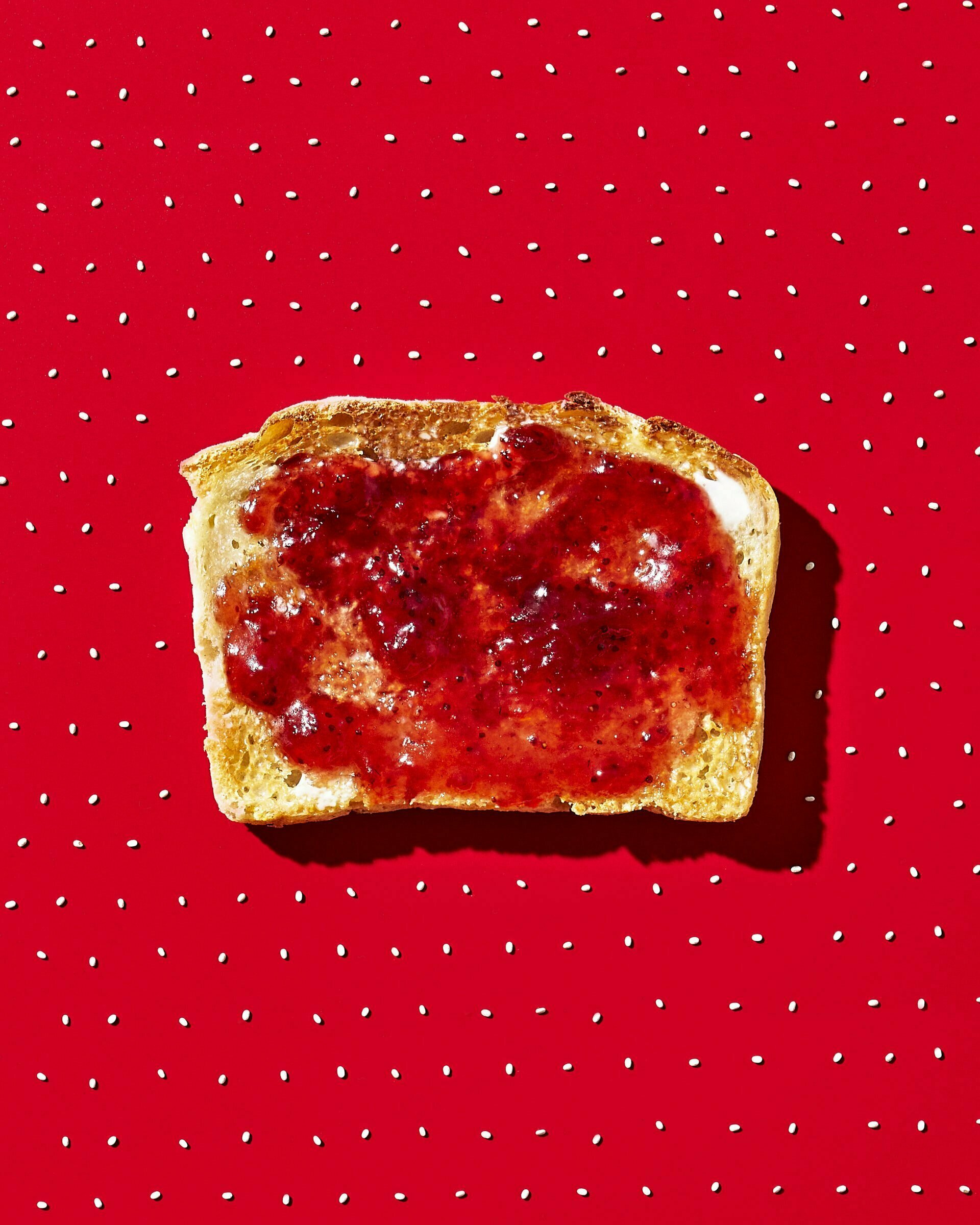 White Bread with butter and strawberry jam on a bright red background with white polka dots